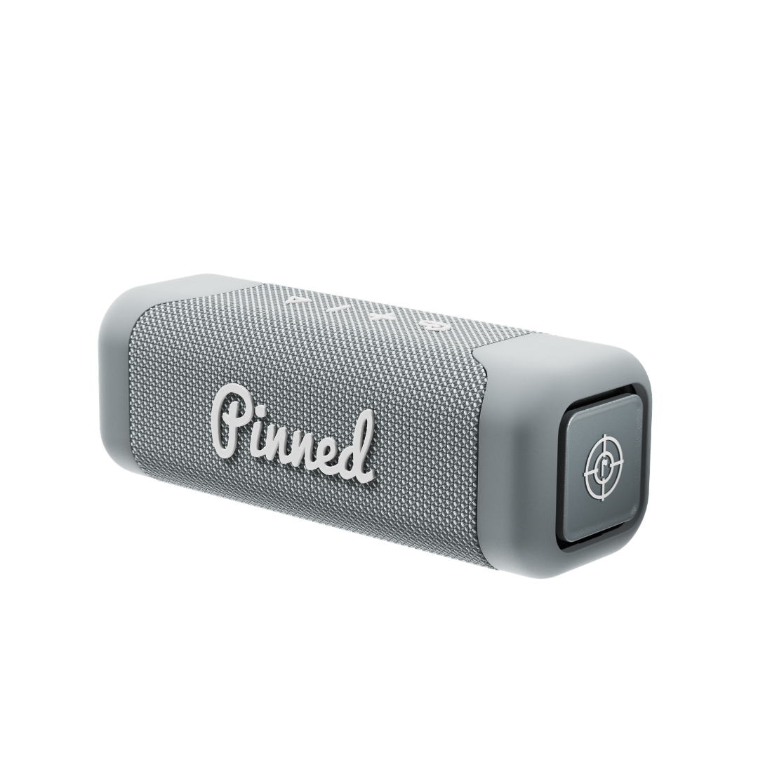 Gray portable speaker with 'Pinned' branding in white on a white background
