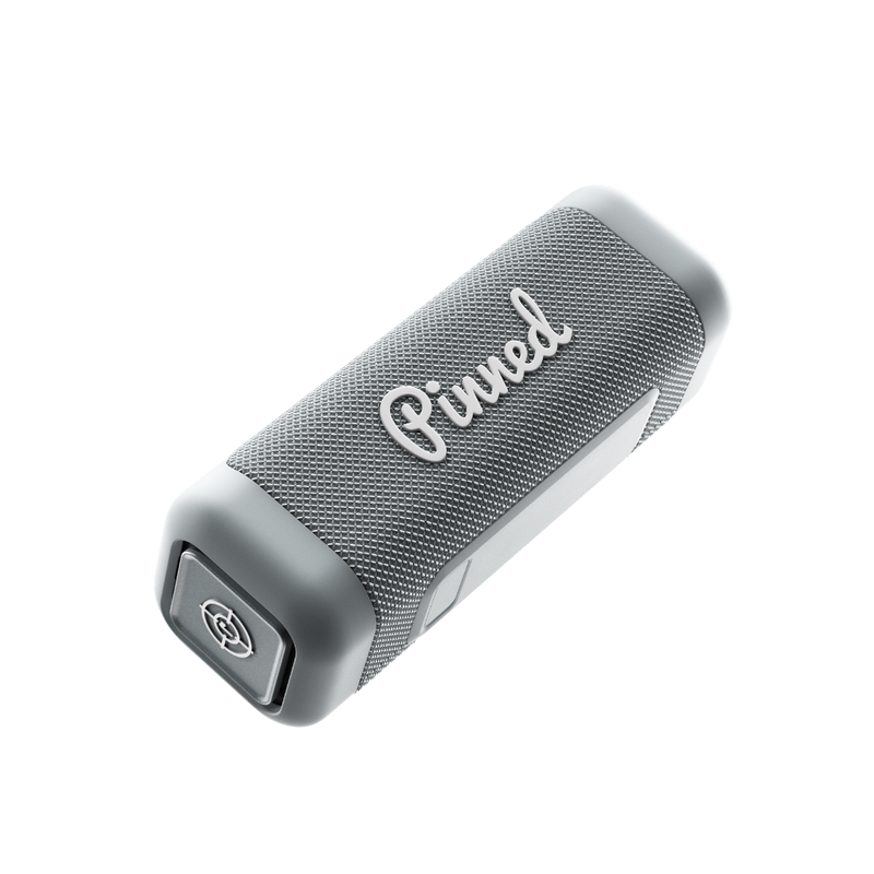 Gray portable speaker with 'Pinned' branding in white on a white background